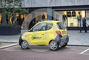Small yellow electric car parked on the street