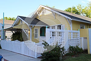 A small yellow house with white fence