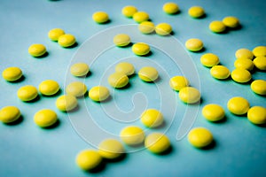 Small yellow orange beautiful medical pharmaceptic round pills, vitamins, drugs, antibiotics on a blue background, texture.