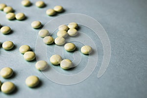 Small yellow orange beautiful medical pharmaceptic round pills, vitamins, drugs, antibiotics on a blue background, texture.