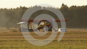 small yellow and red private jet starts engine, propeller start spin, there is lot of smoke around aircraft. shot was