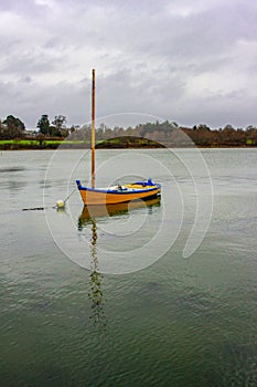 a small yellow sailboat at anchor