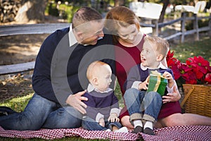 Small Young Family Opening Christmas Gifts in the Park