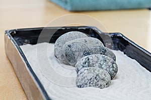 Small zen decoration with sand and granite stones that calm and are staggered. In the background a lime green towel