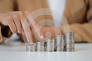 Smart and active asian businesswoman hands walking on stacking coin growing on white table and white background, meaning of