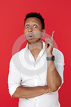 Smart african american young man holding finger up over red background. Idea concept.