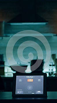 Smart application on tablet placed on kitchen desk in empty house