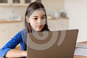 Smart arab girl schooler sitting at modern laptop from home