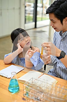 Smart Asian girl asking some scientific questions and discussing with her male science teacher