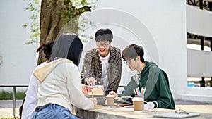 Smart Asian male college student is tutoring math to his friends at a campus park