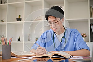 Smart Asian male medical student focuses on reading a book in the medical school library