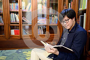 Smart Asian man student reading book in library