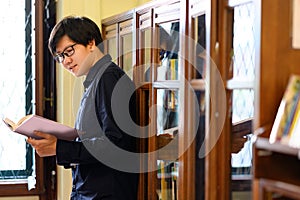 Smart Asian man student reading book in library