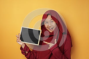 Smart Asian Muslim Teenage Girl Smiling at Camera and Showing Empty Blackboard