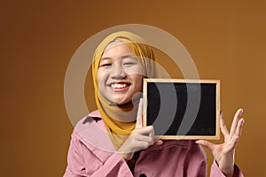 Smart Asian Muslim Teenage Girl Smiling at Camera and Showing Empty Blackboard