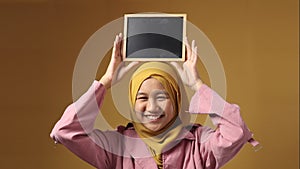 Smart Asian Muslim Teenage Girl Smiling at Camera and Showing Empty Blackboard