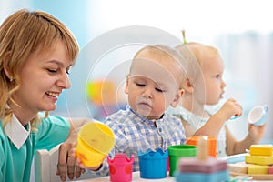 Smart babies in day care. Group of kids playing toys with kindergarten teacher. Children lesson in creche