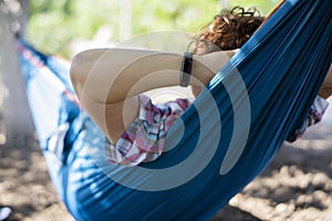 SMART BAND WRIST WEARABLE ON A LADY IN HAMMOCK RELAXING IN NATURE DURING SUMMER