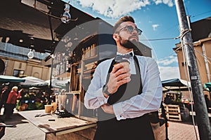 Smart barista in glasses has a break at his own coffeeshop.