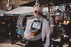 Smart barista in glasses has a break at his own coffeeshop.