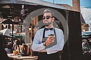 Smart barista in glasses has a break at his own coffeeshop.