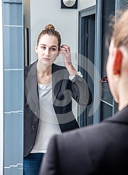 Smart beautiful young woman looking at her reflection in mirror