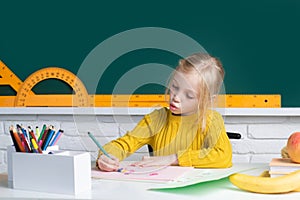 A smart blonde school girl sitting at the table, preparing for the exam. Genius child, knowledge day. Kids education and