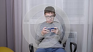 Smart Boy in Glasses Watching a Video in a Mobile App on a Smartphone.