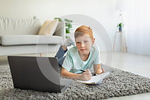 Smart boy schooler watching educational course on laptop