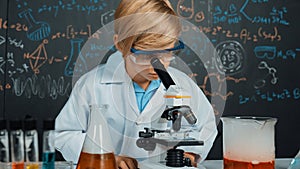 Smart boy using microscope analysis sample at science laboratory. Erudition.