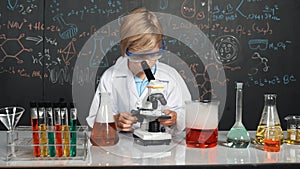 Smart boy using microscope analysis sample at science laboratory. Erudition.