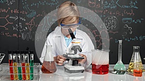 Smart boy using microscope analysis sample at science laboratory. Erudition.