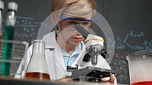 Smart boy using microscope analysis sample at science laboratory. Erudition.