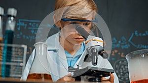 Smart boy using microscope analysis sample at science laboratory. Erudition.