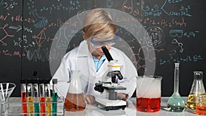 Smart boy using microscope analysis sample at science laboratory. Erudition.