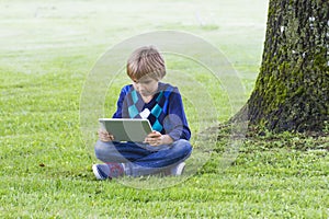 Smart boy using a tablet outdoors. Technology, lifestyle, education, people concept