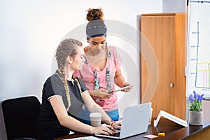 Smart business african american woman showing report on digital tablet to her colleague in office