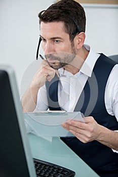 Smart businessman in white shirt verifying information from paper