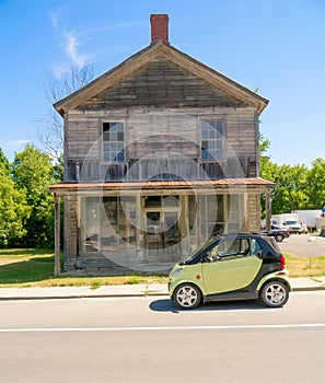 Smart Car in front of old wooden house.