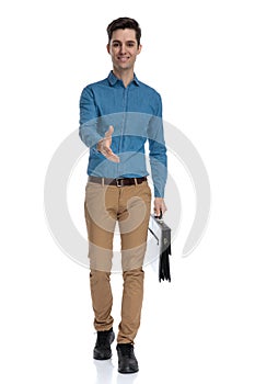Smart casual man in blue shirt holding suitcase and shaking hand