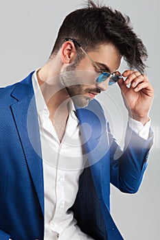 Smart casual man fixing his sunglasses looks down to side