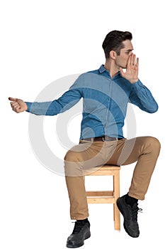 Smart casual man whispering to side and pointing finger