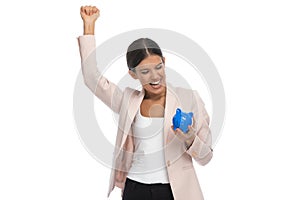 Smart casual woman celebrating and showing blue piggy bank