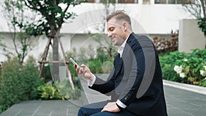 Smart caucasian businessman looking at smart phone and checking report. Urbane.