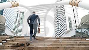 Smart caucasian businessman walking up stairs surrounded by urban view. Urbane.