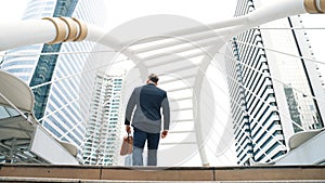 Smart caucasian businessman walking up stairs surrounded by urban view. Urbane.