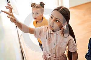 Smart caucasian girl using interactive whiteboard with her finger