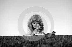 Smart child boy reading book in park outdoor. Clever kids read book in nature background.