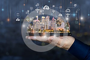 Smart city technologies concept with digital tablet and night megapolis city skyscrapers with digital cloud icons on human hand
