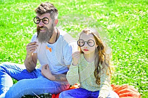 Smart and clever concept. Dad and daughter sits on grass at grassplot, green background. Child and father posing with